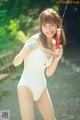 A woman in a white bathing suit holding a water gun.