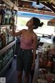 A woman standing in front of a bar filled with bottles of alcohol.