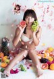 A woman sitting on a bed holding a bunch of fruit.