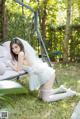 A woman in a white dress sitting on a swing.