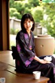 A woman in a kimono sitting on a table with a cup of tea.