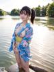 A woman in a blue kimono standing in the water.