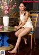 A woman sitting on a chair next to a table with flowers.