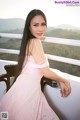 A woman in a pink dress sitting on a balcony.