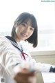 A woman in a school uniform sitting at a desk.