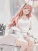 A girl with long pink hair sitting on a bed.