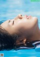 A woman floating in a pool with her eyes closed.